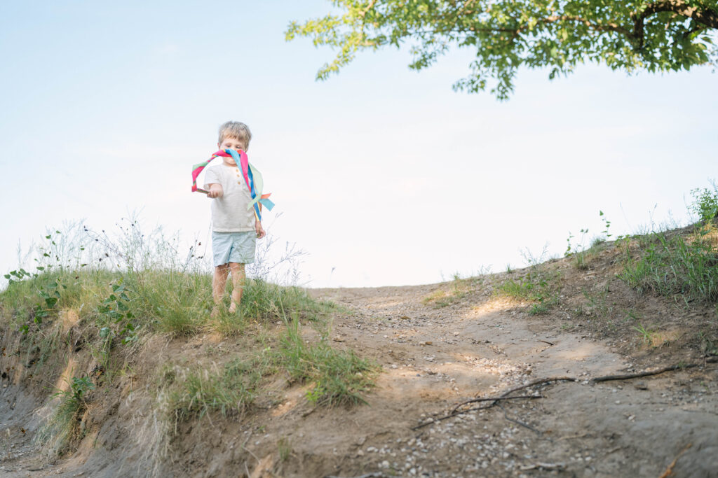 portrait of young boy with rainbow streamers on hill